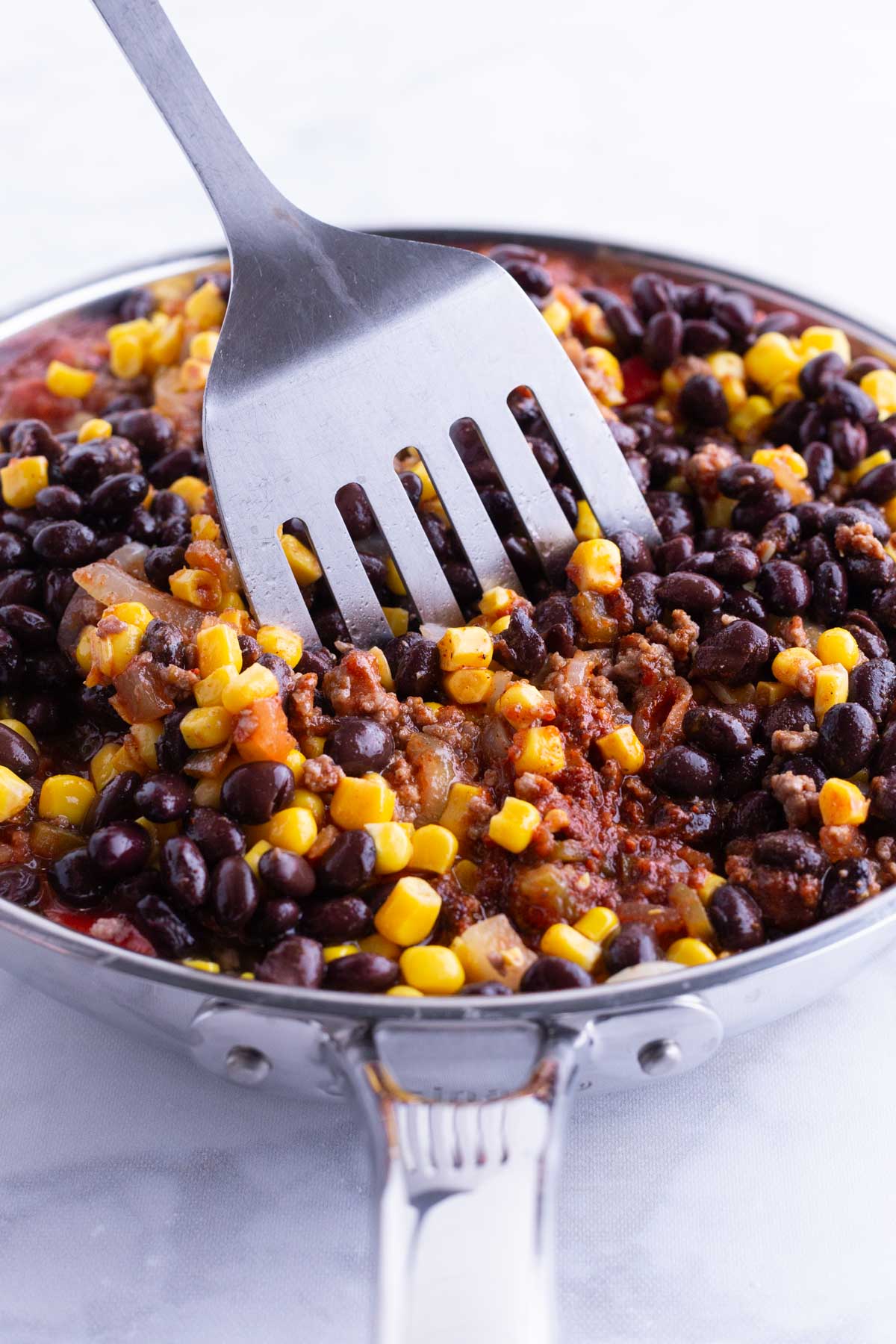 Corn, beans, and seasonings are mixed into the taco mixture.