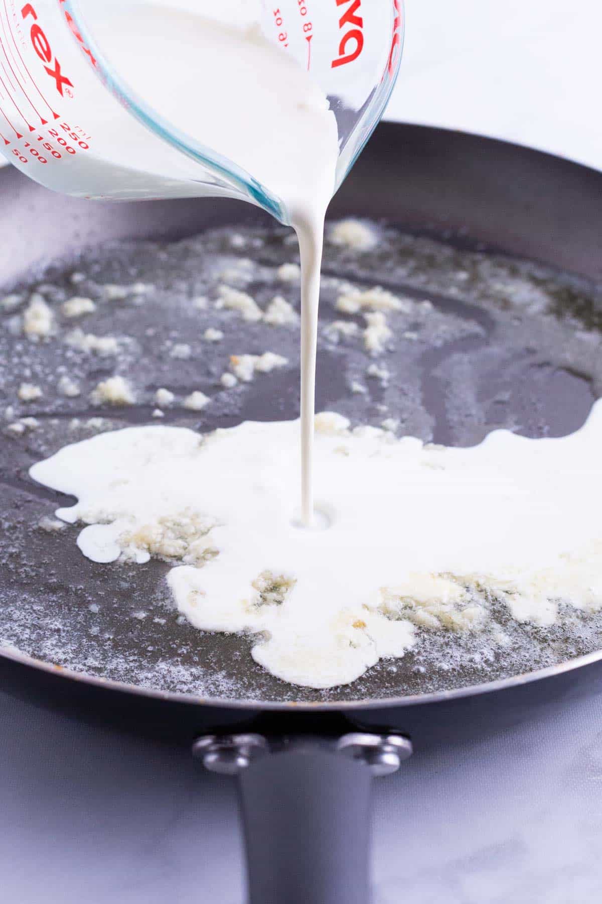 Cream is poured into the skillet with the garlic.