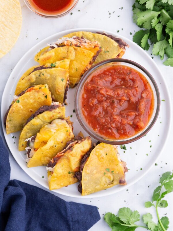 A tray of corn tortilla quesadillas are served on a tray with salsa.