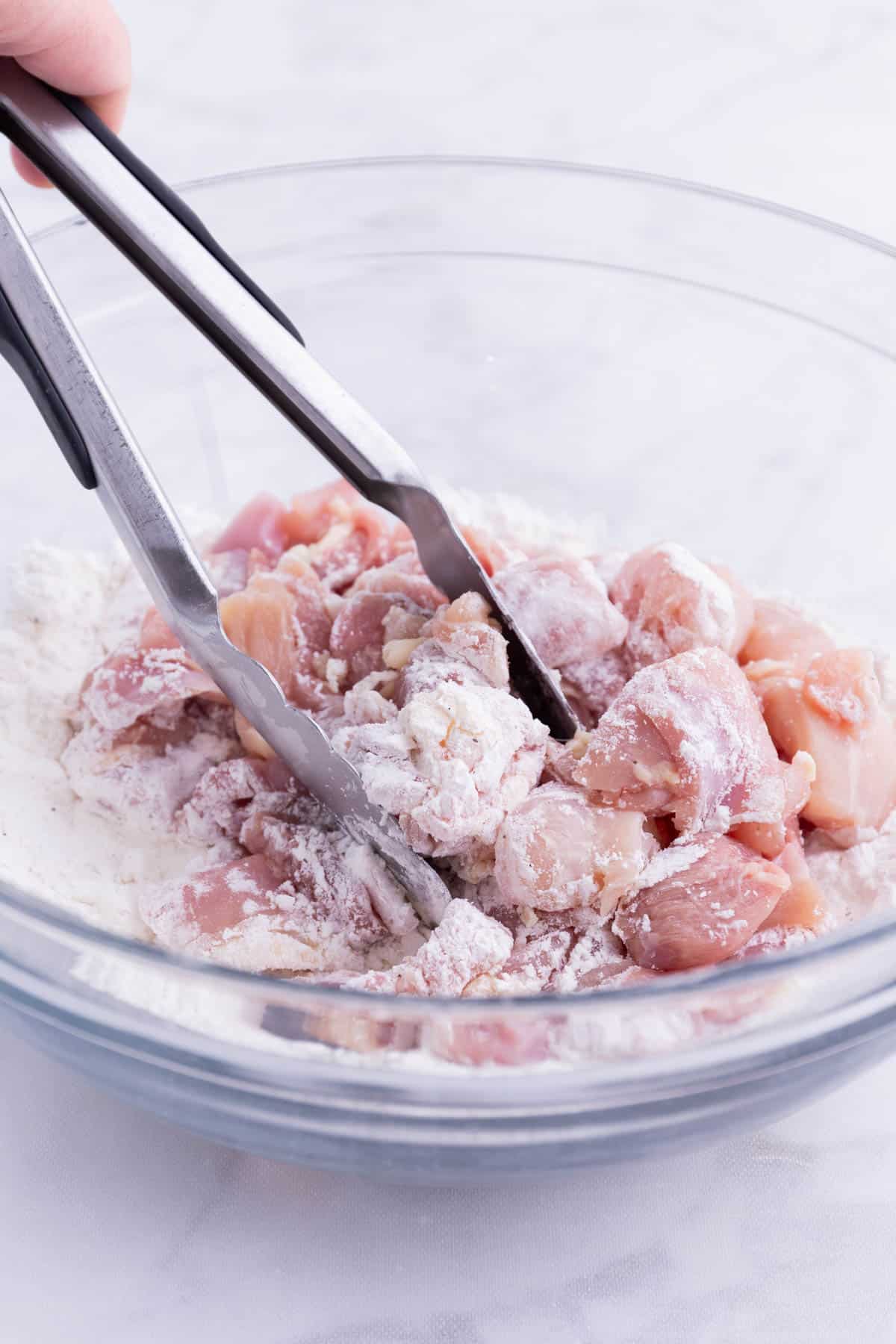 Chicken pieces are coated in the flour mixture.