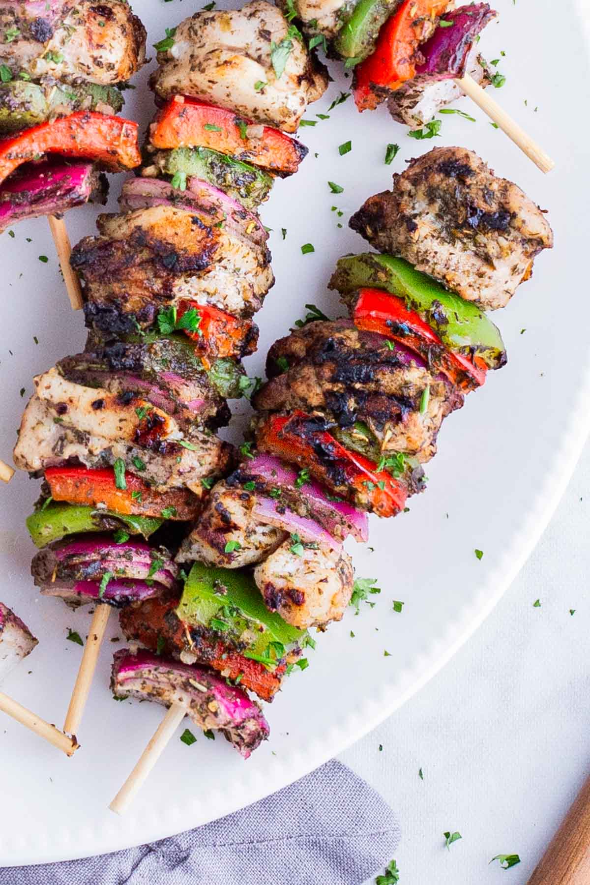 Greek seasoned chicken are grilled with sliced vegetables on a skewer.
