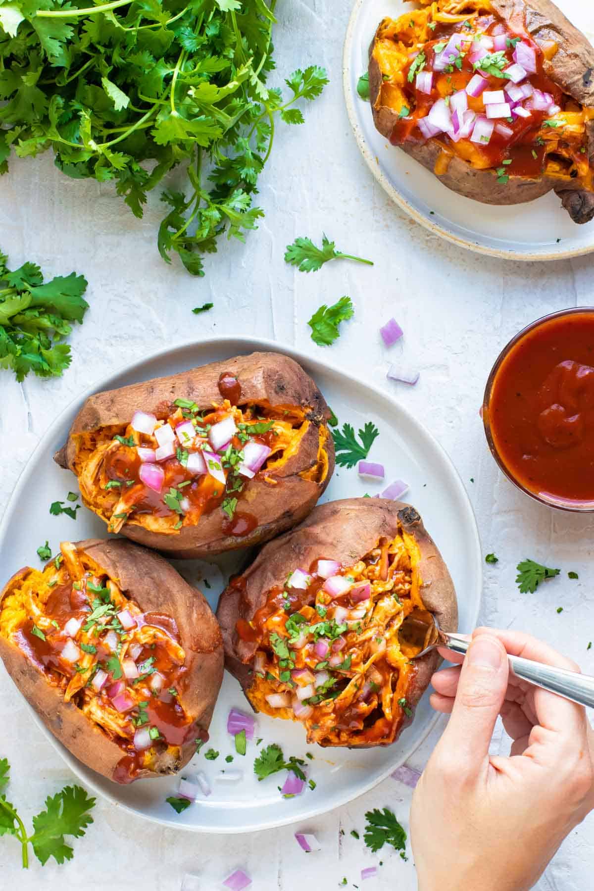 Chicken Stuffed Sweet Potatoes being eaten with a fork and BBQ sauce to the side.