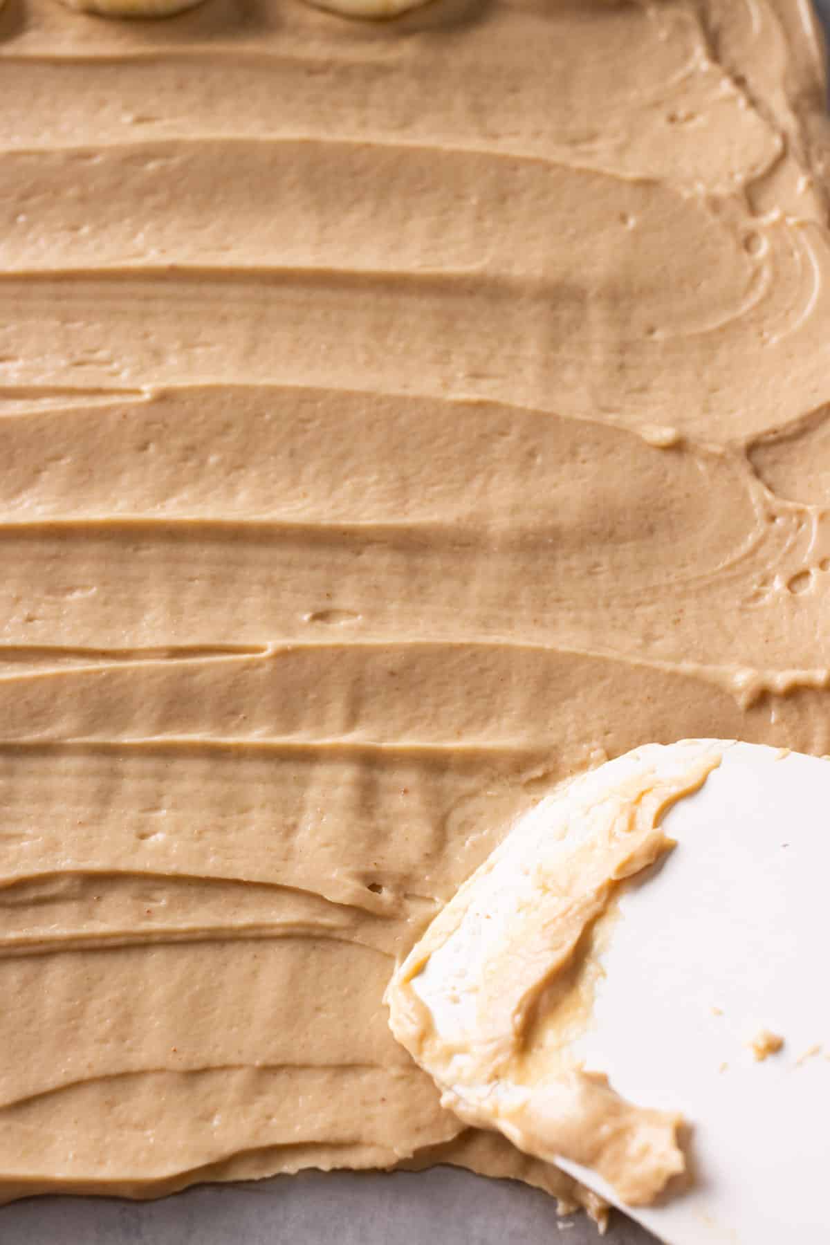 Peanut butter flavored Greek yogurt is spread in a baking tray.