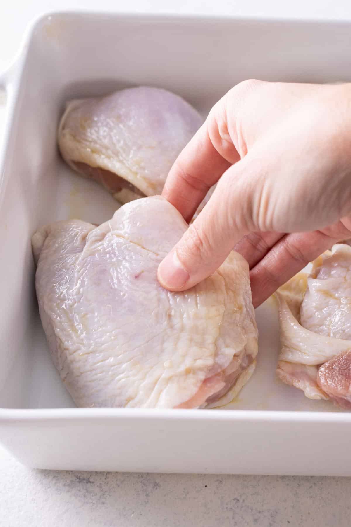 Chicken thighs are placed in a baking dish.