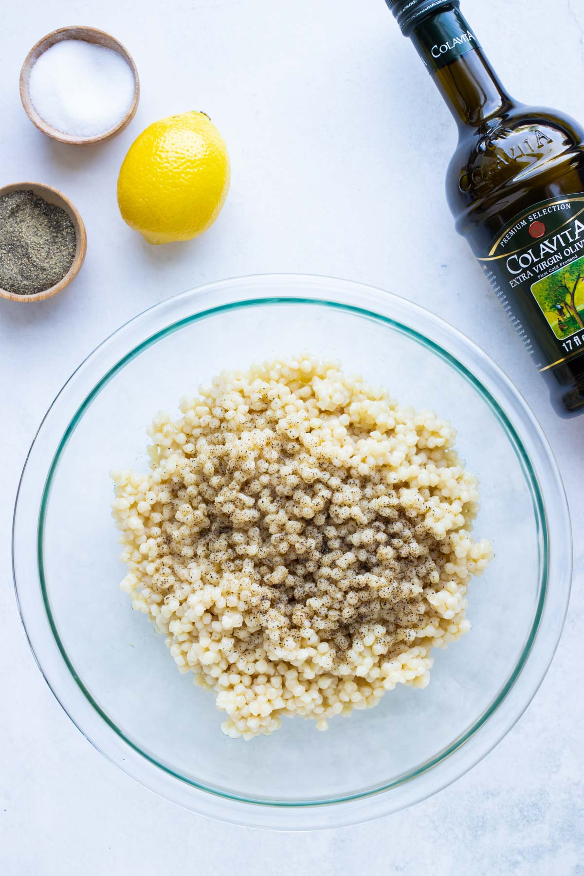 Cooked couscous is seasoned with oil, lemon, and salt.