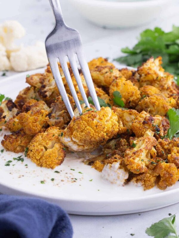 A fork picks up a piece of curry-roasted cauliflower.