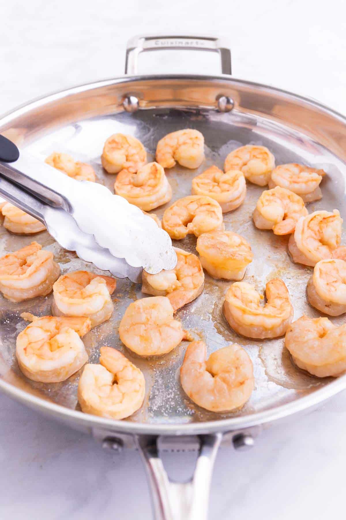 Shrimp is cooked in a skillet.