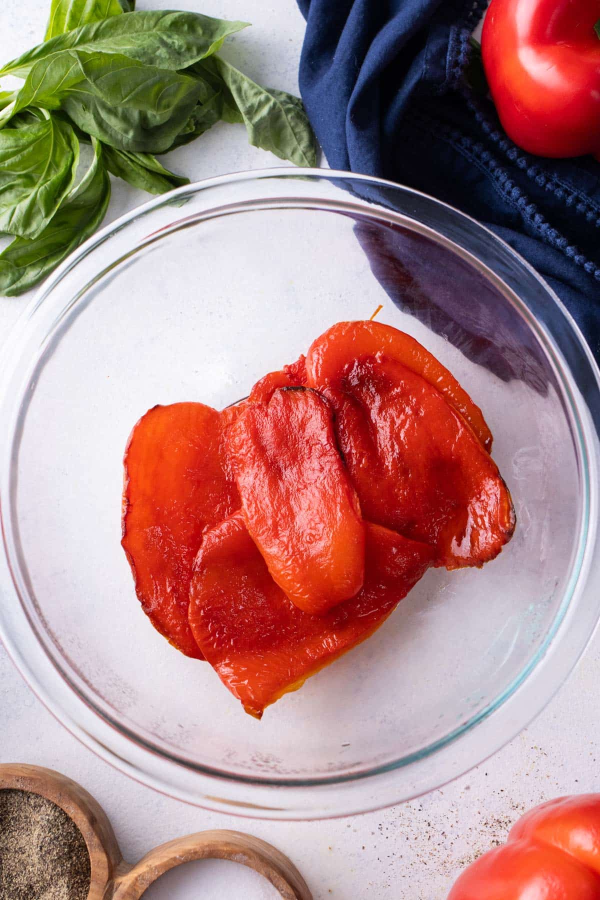 Roasted red peppers rest in a bowl before peeling.