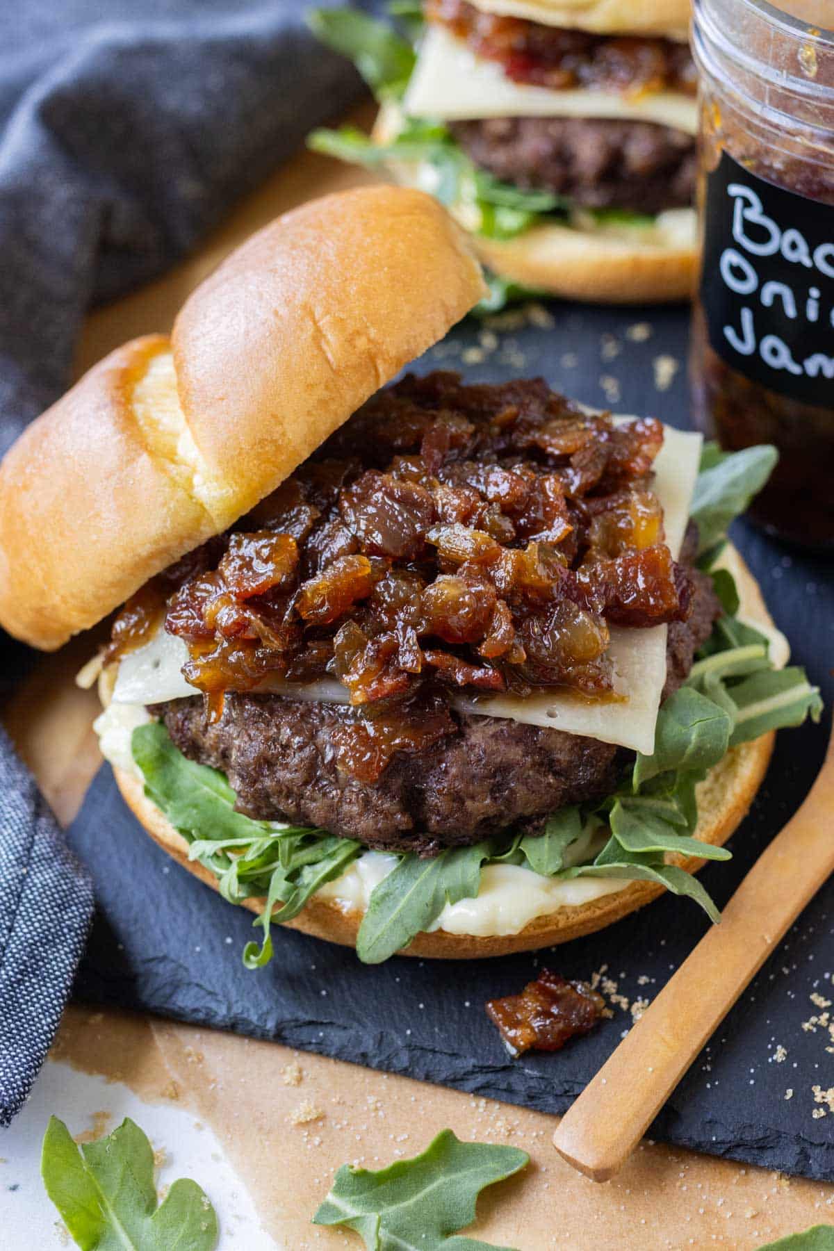 Arugula, swiss cheese, and homemade bacon onion jam is served on a hamburger.