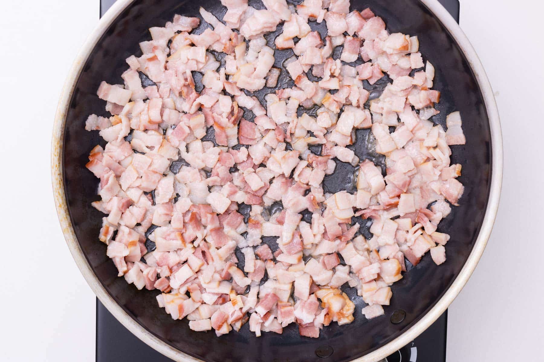 Bacon is cooked in a skillet.