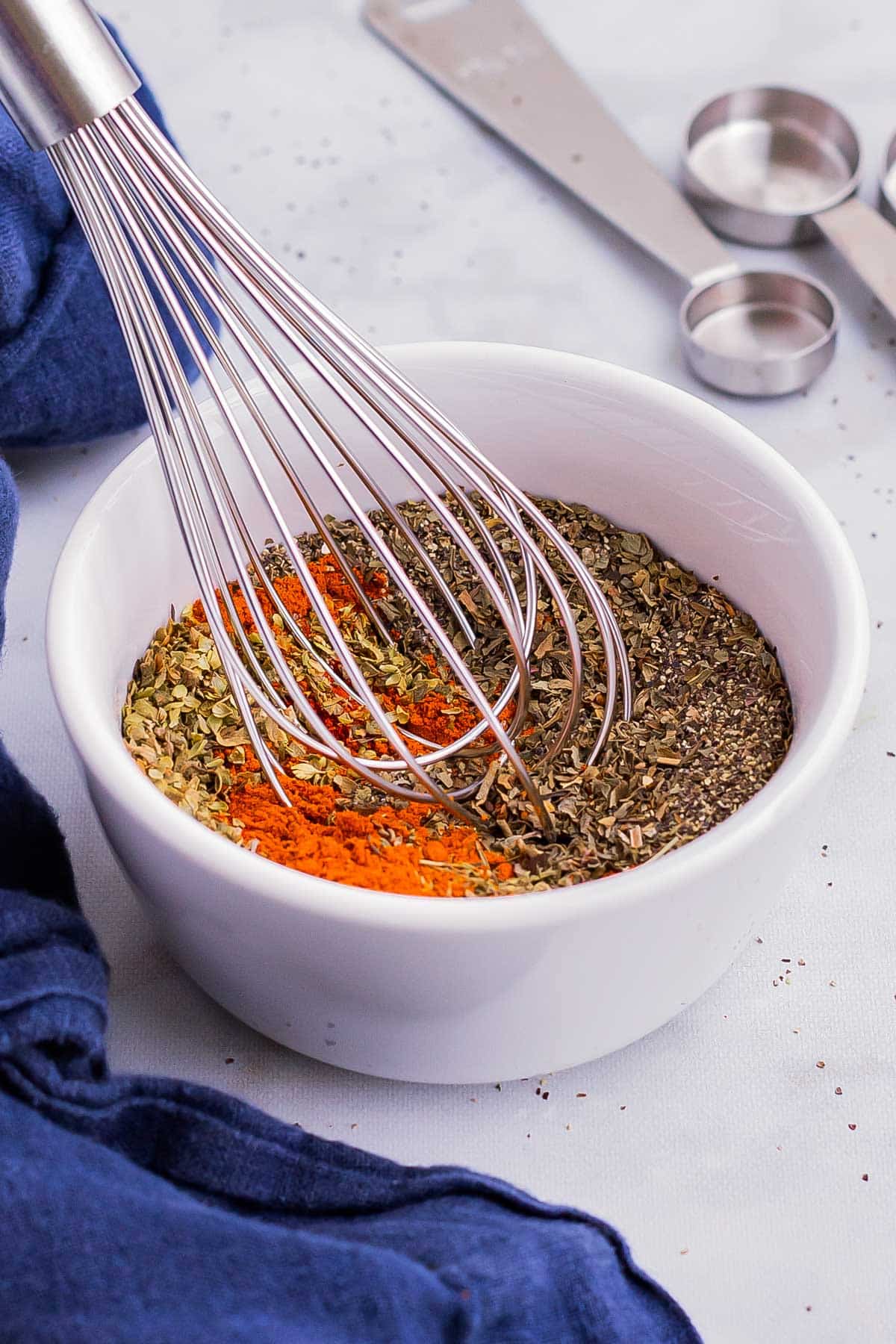 A whisk is mixing up a Cajun seasoning recipe in a white bowl to use for blackening.