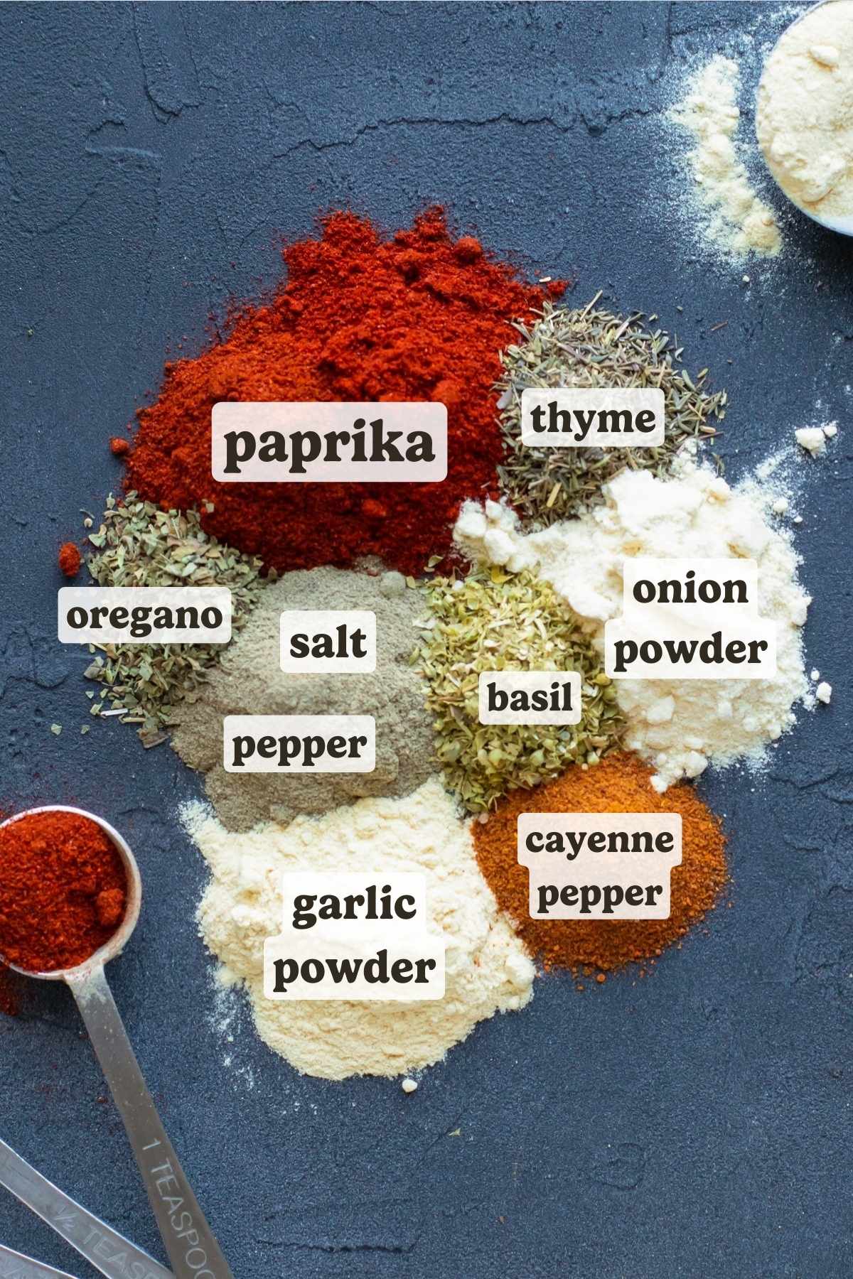 The ingredients for a homemade Cajun seasoning recipe are on a table with measuring spoons.