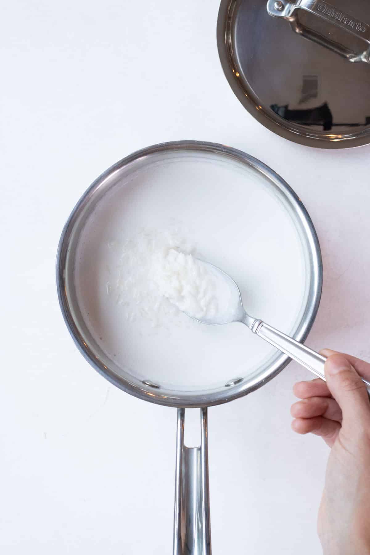 Coconut milk and rice are combined in a skillet.