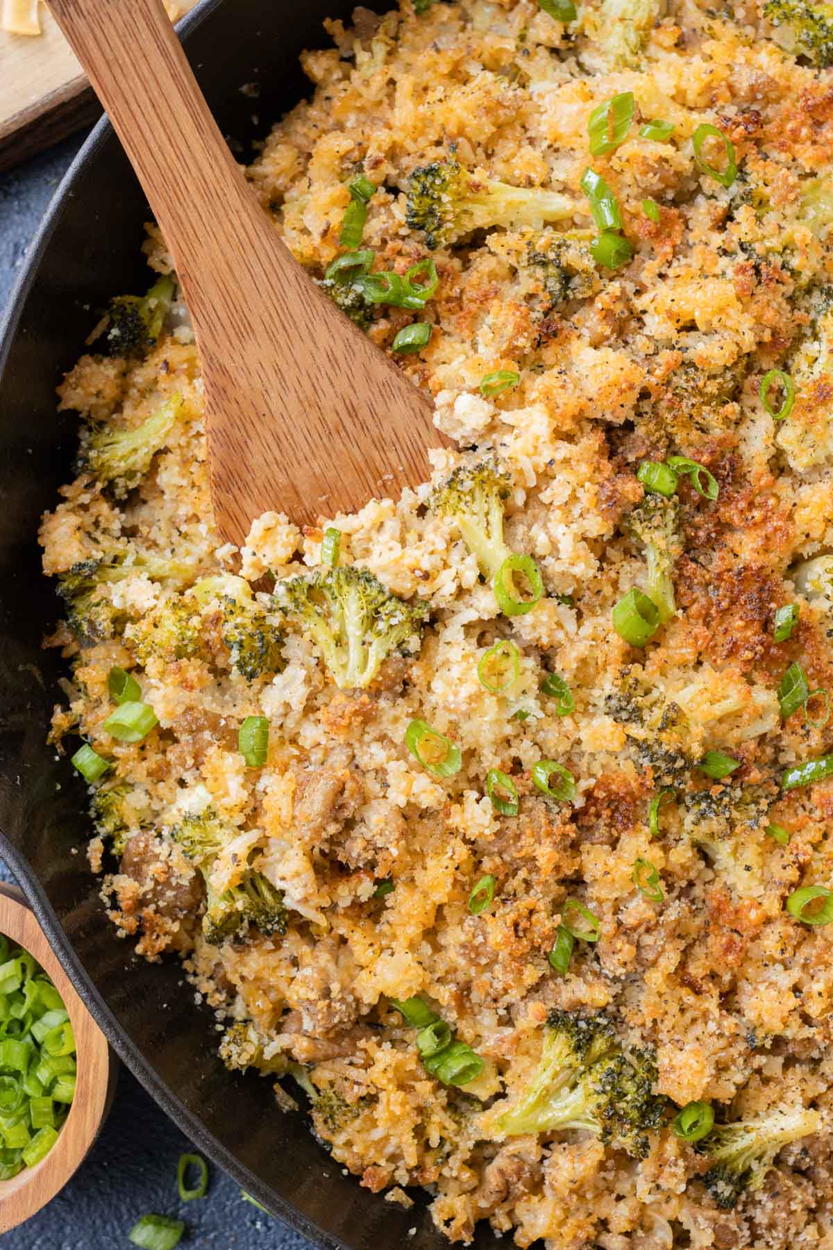 A wooden spoon is used to serve ground turkey broccoli cheese rice.