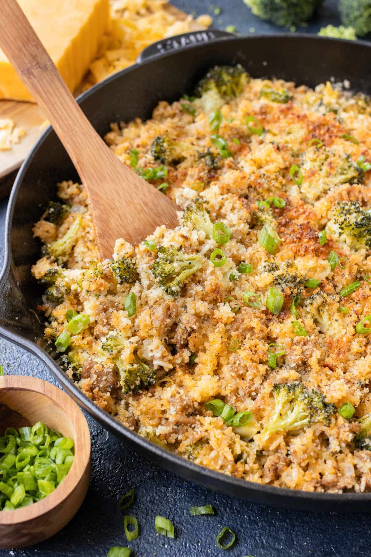 A wooden spoon is used to serve the broccoli rice mixture.