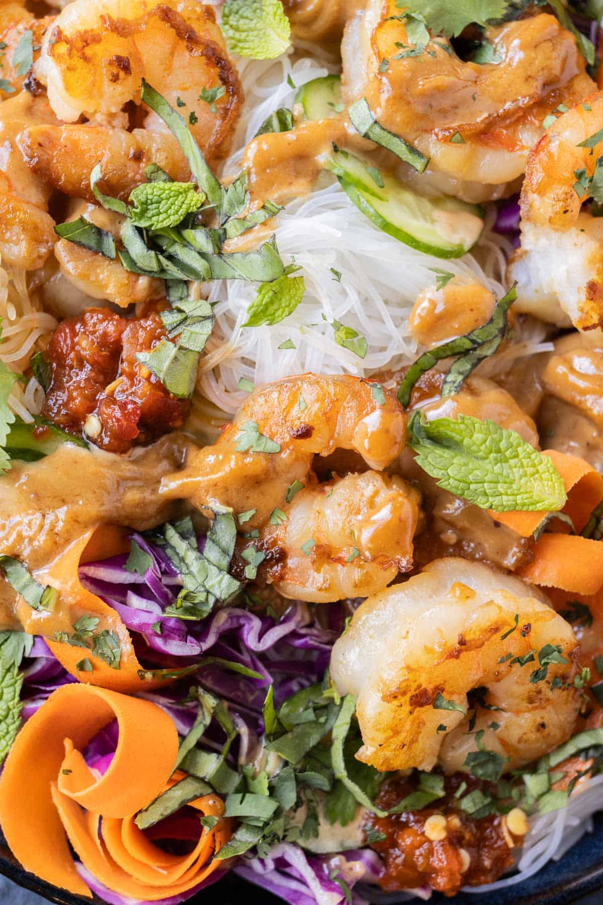 Seared shrimp in a spring roll in a bowl recipe with peanut sauce drizzled on top.