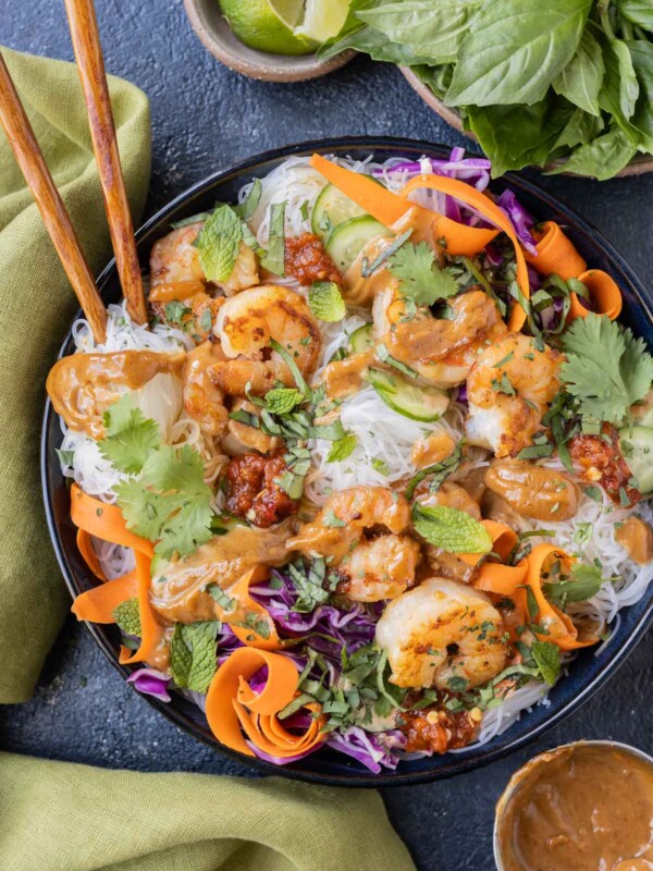 A spring roll in a bowl recipe is served with peanut sauce and a side of limes.