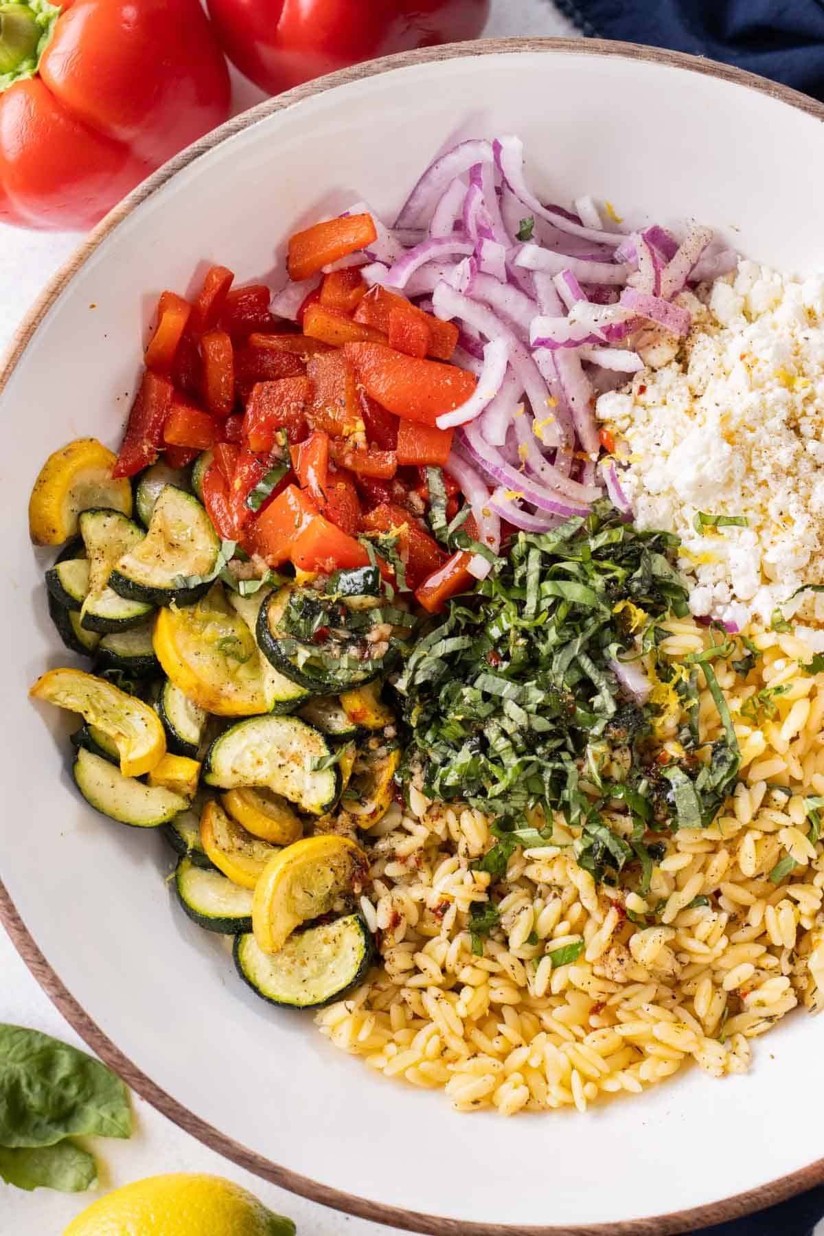 All of the components for Summer Orzo Pasta Salad ready to be mixed in a white bowl.