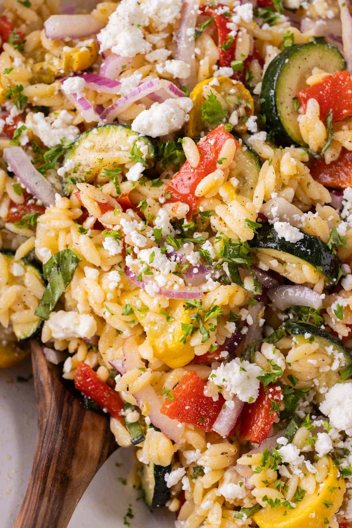 The lemon orzo pasta salad is tossed in a large bowl.