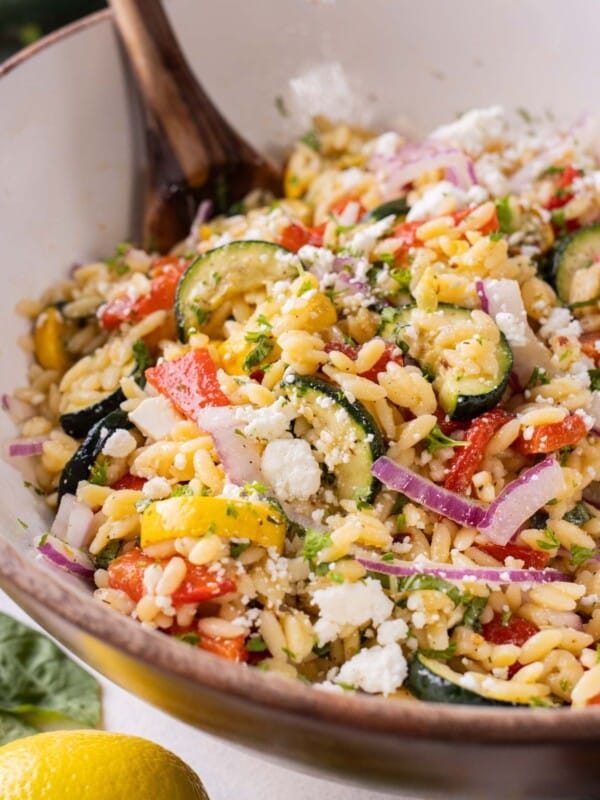 The lemon orzo pasta salad is tossed in a large bowl.
