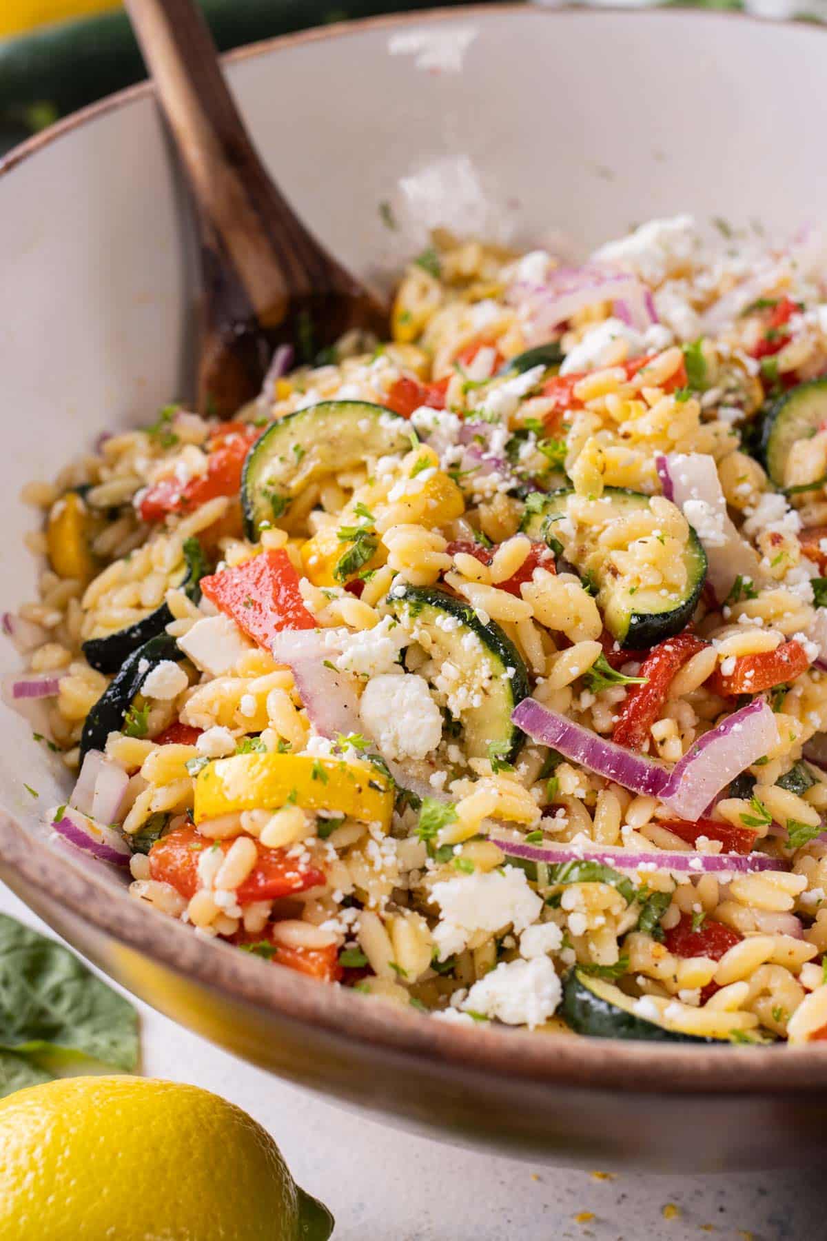 Lemon Orzo Pasta Salad with Feta RECIPE served in a bowl with a wooden spoon.