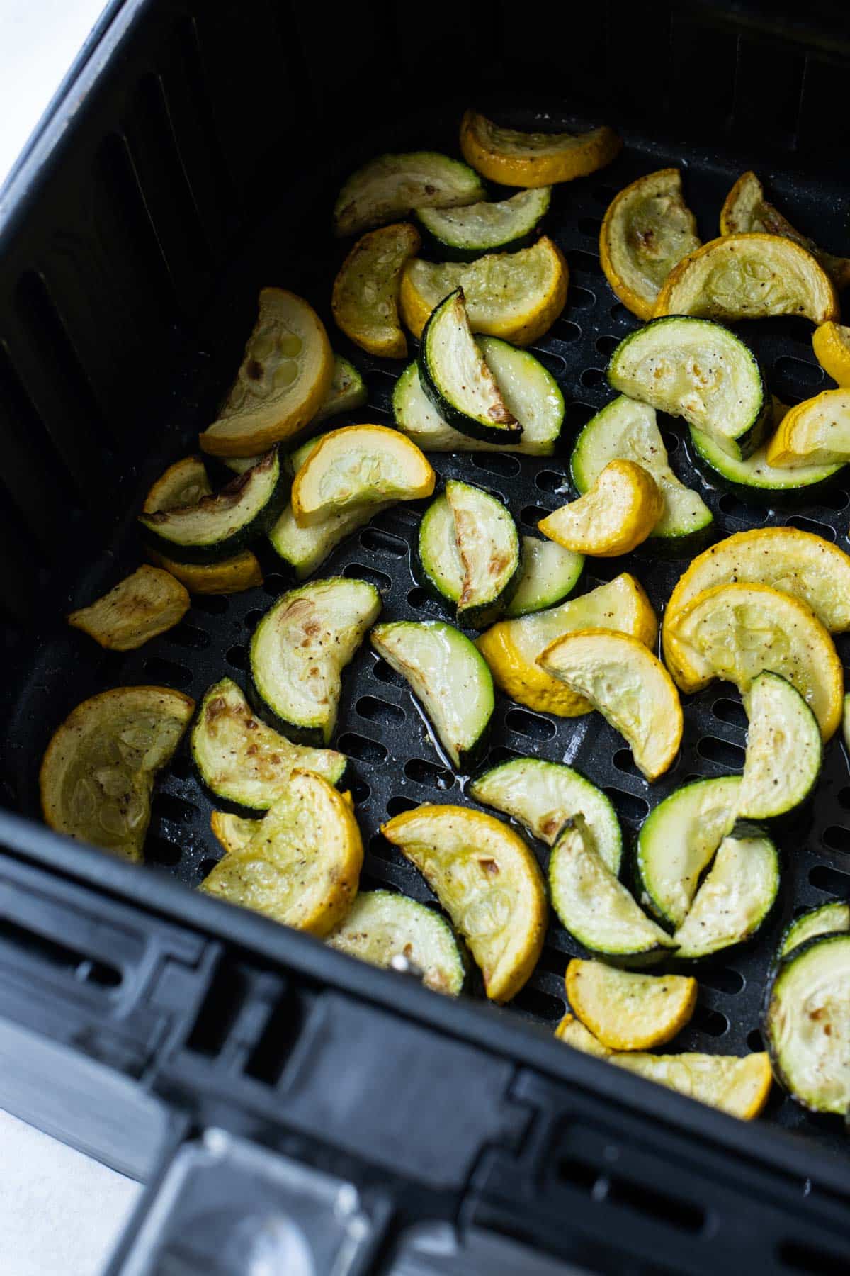 Sliced squash is cooked in an air fryer.