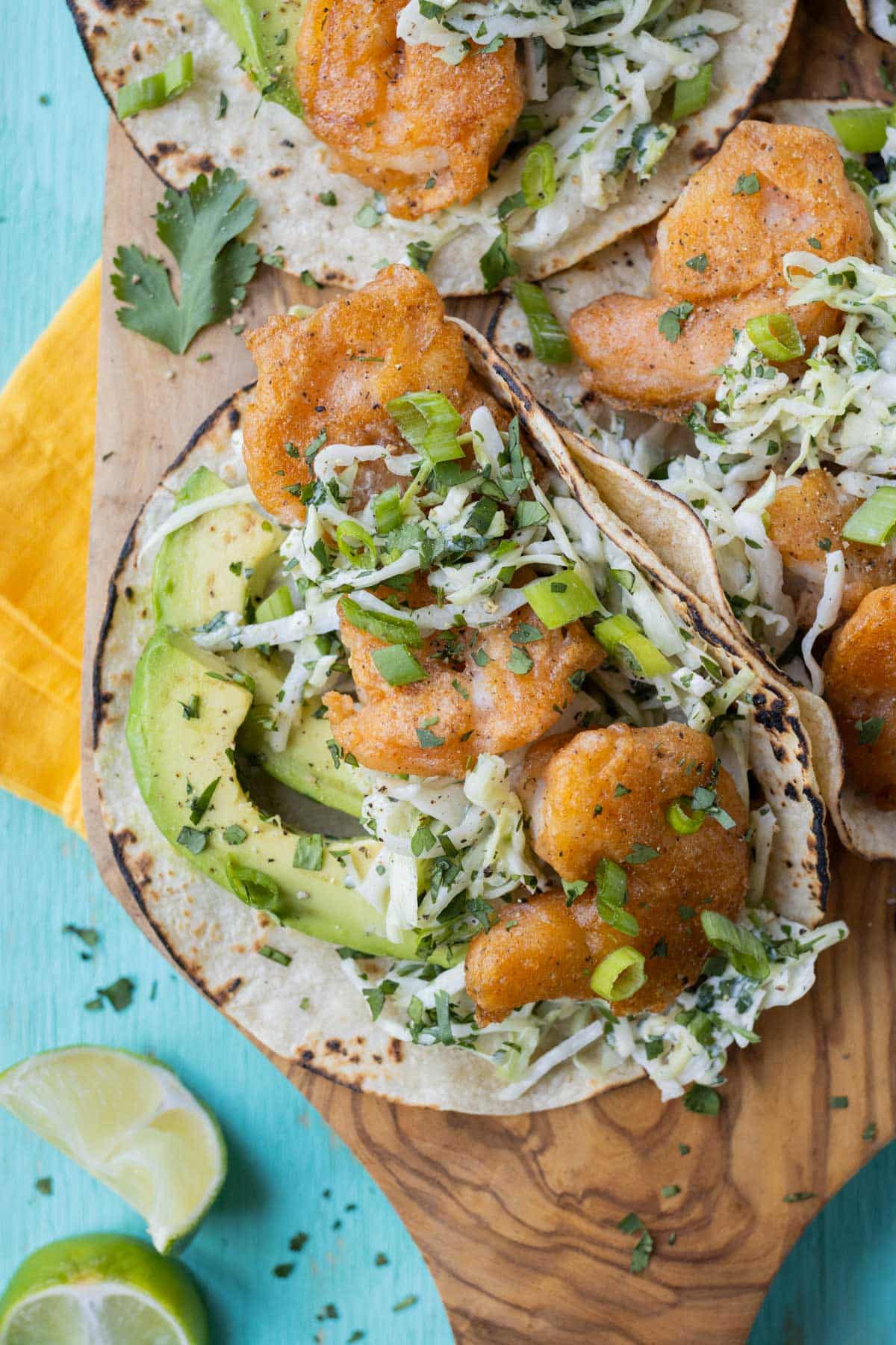 Baja Shrimp Tacos RECIPE served on a wooden platter topped with cilantro and green onion.