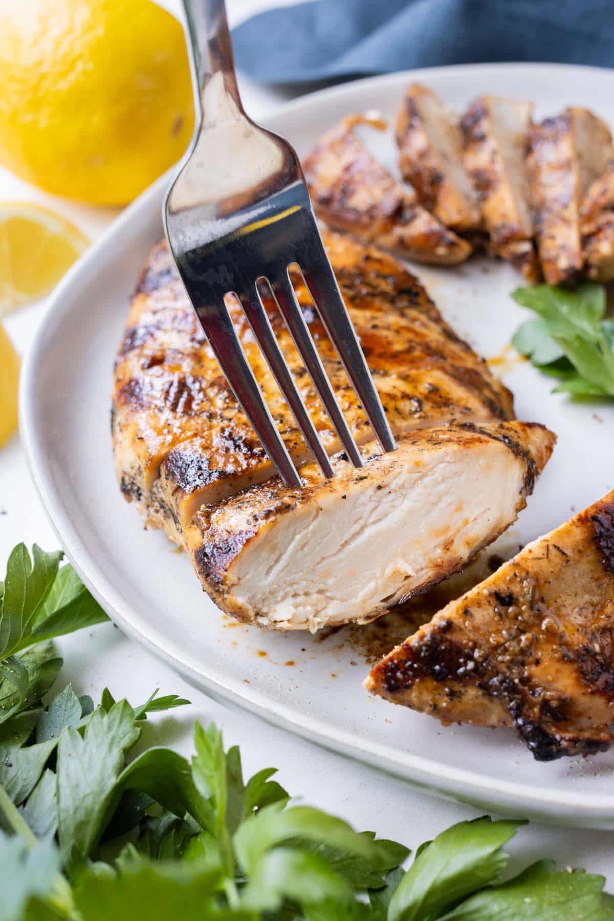 Balsamic grilled chicken breast is sliced on a plate.