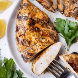 Balsamic grilled chicken breast is sliced on a plate.