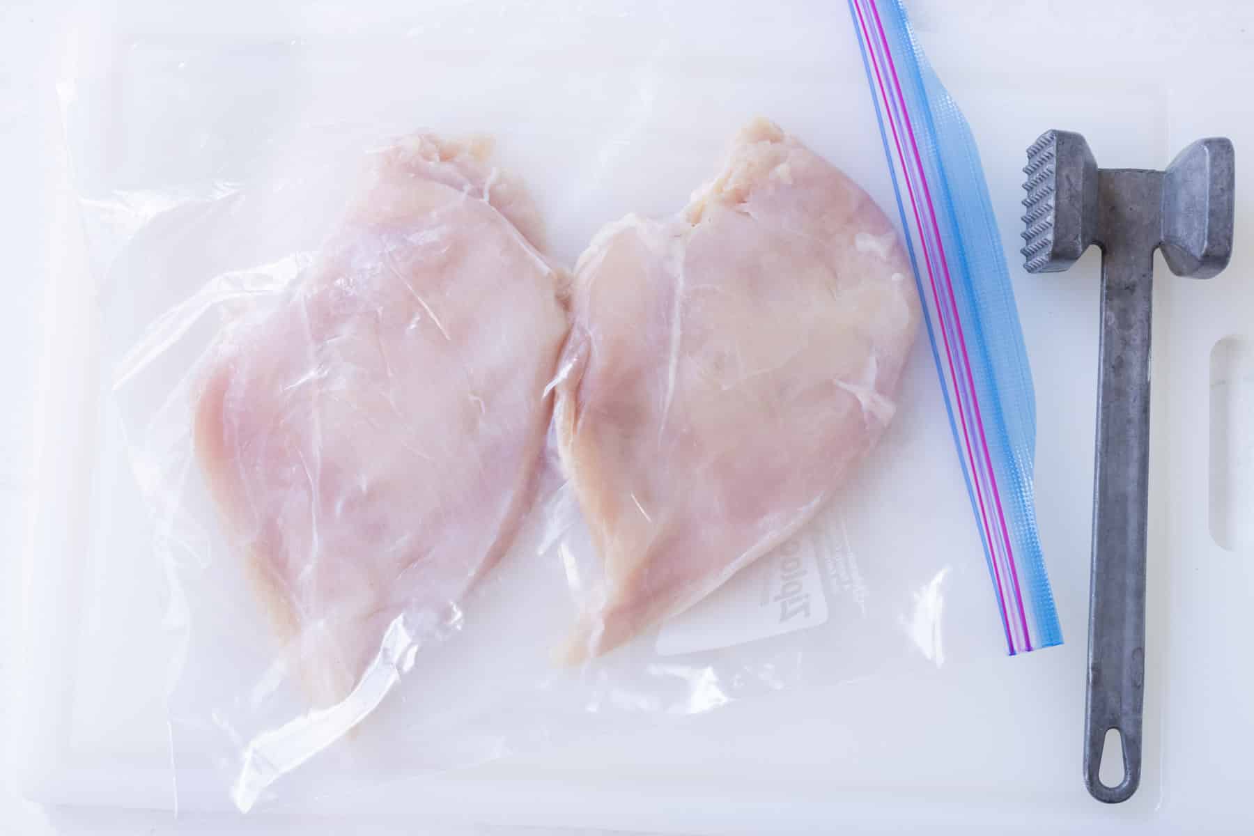 Chicken breasts are pounded thin in a bag.