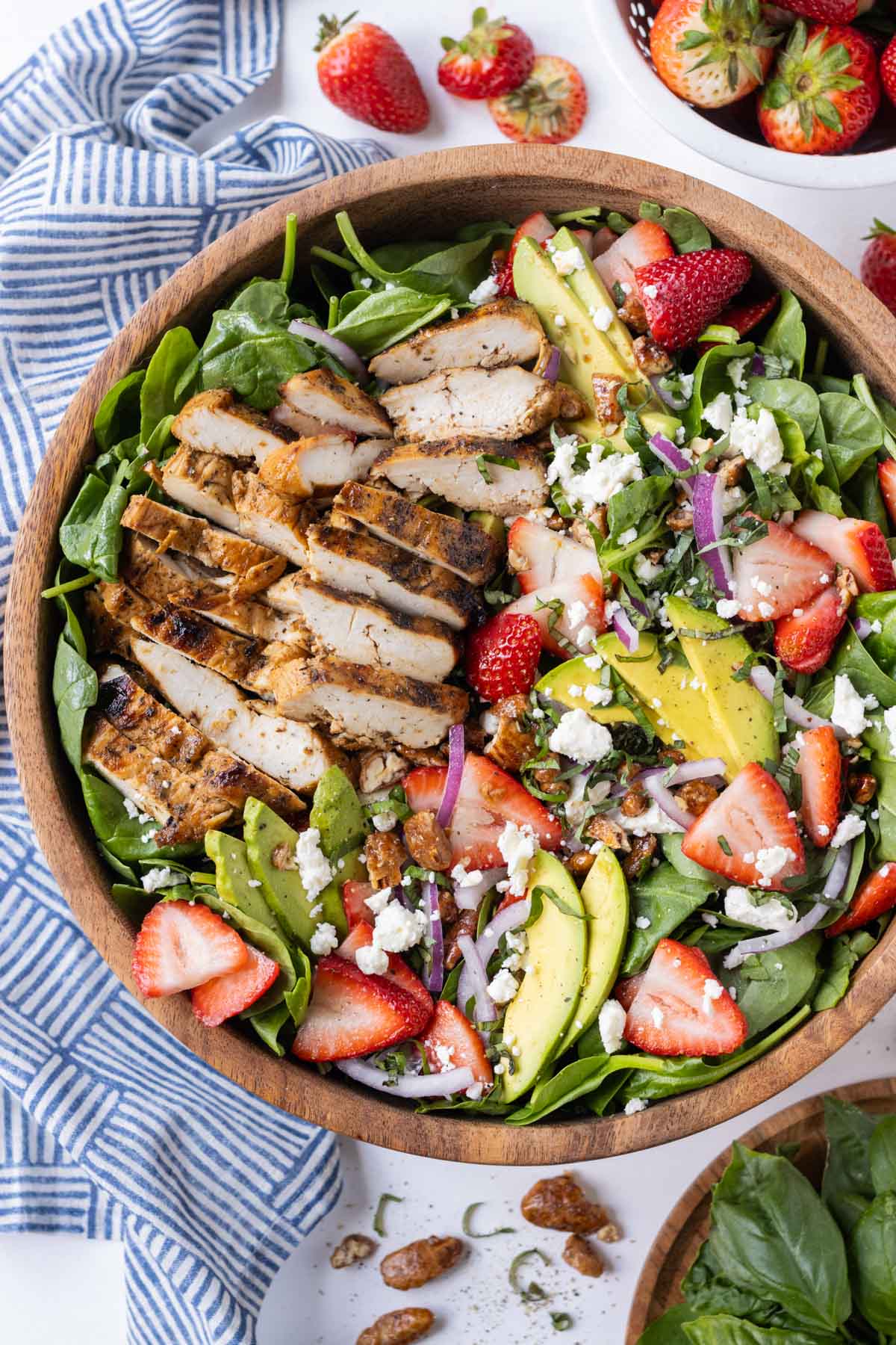 Grilled chicken is added on top of a spinach salad with strawberries and a balsamic vinaigrette.