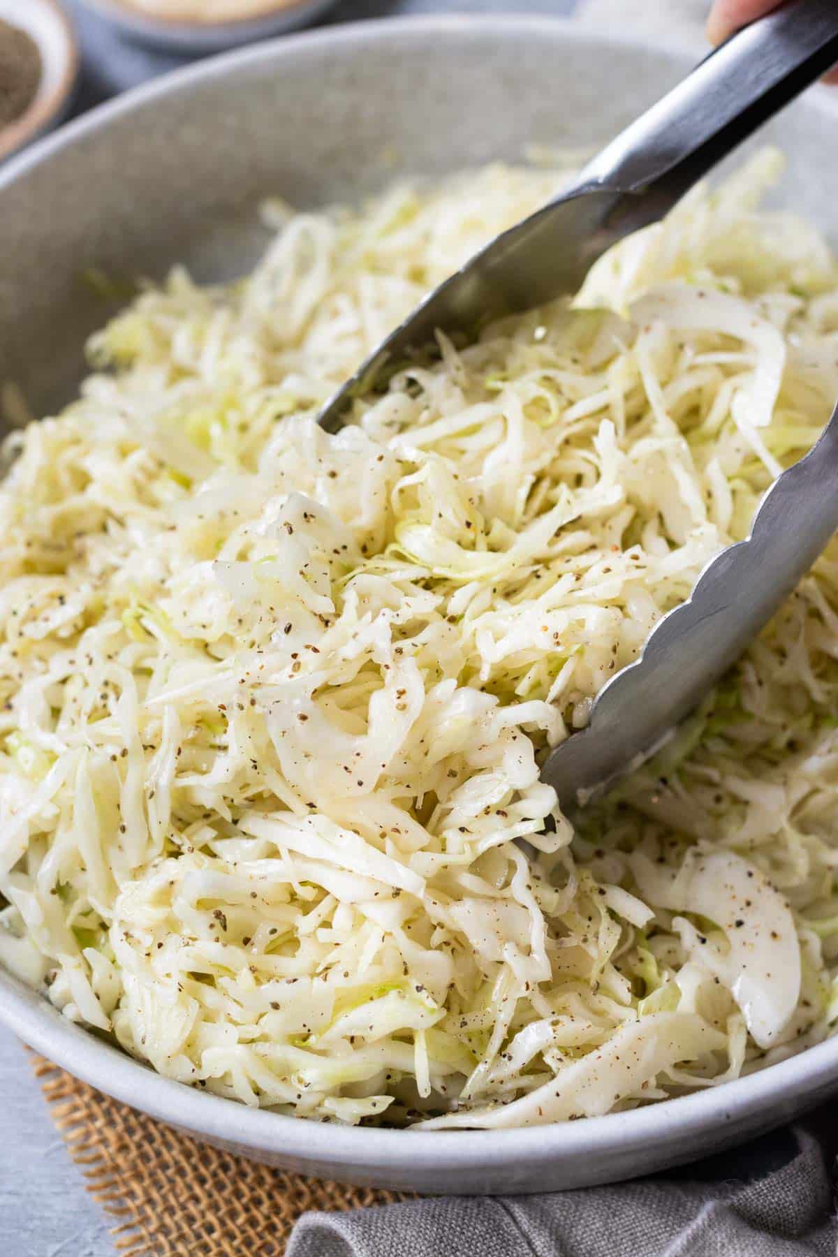 Apple Cider Vinegar Slaw RECIPE with metal tongs.