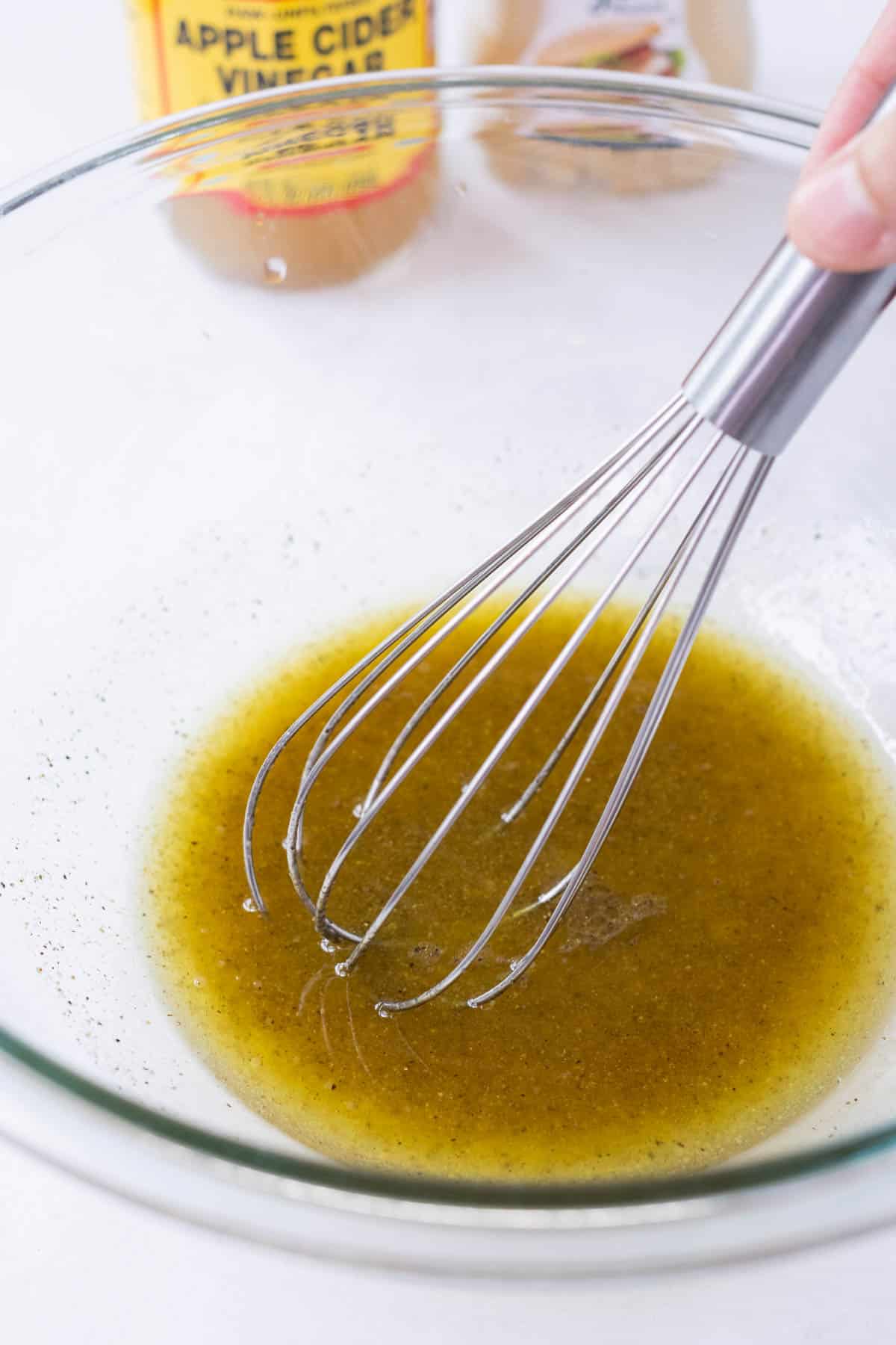 The dressing is whisked together in a glass bowl.