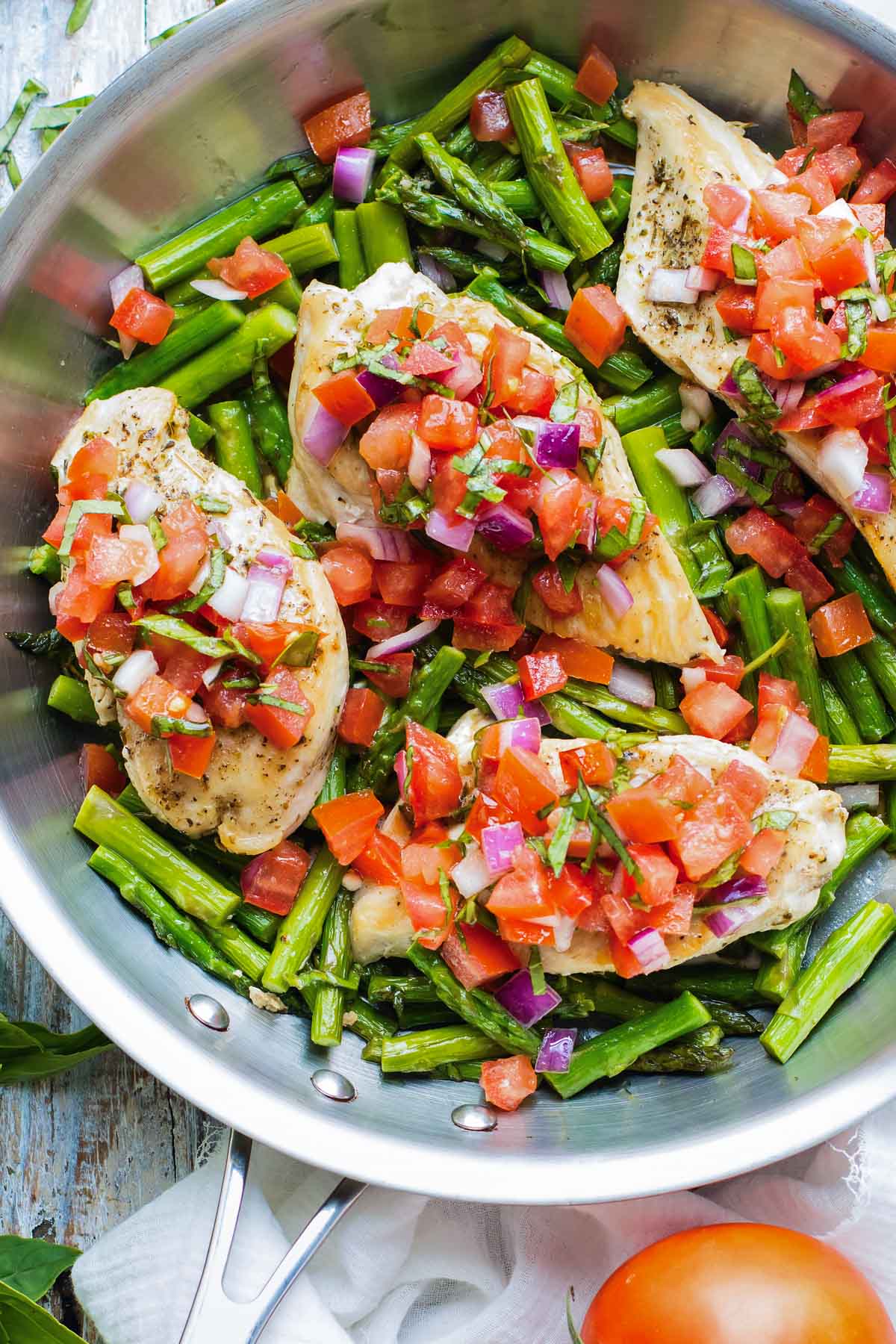 Chicken and asparagus are cooked in a pan then topped with bruschetta.