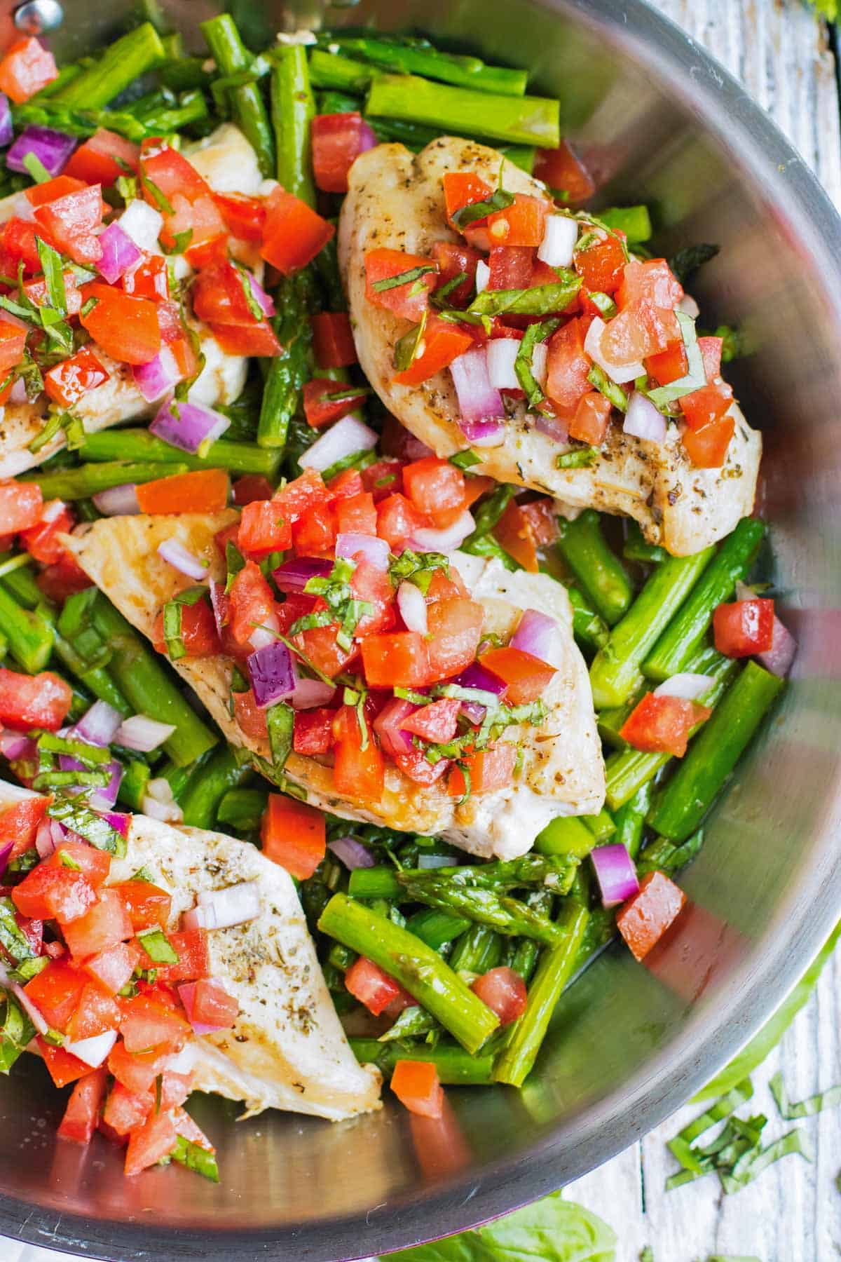 Chicken and asparagus are cooked in a pan then topped with bruschetta.