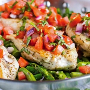 Chicken and asparagus are cooked in a pan then topped with bruschetta.