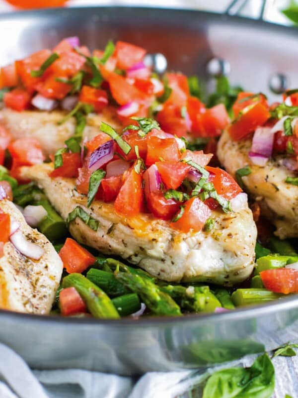 Chicken and asparagus are cooked in a pan then topped with bruschetta.