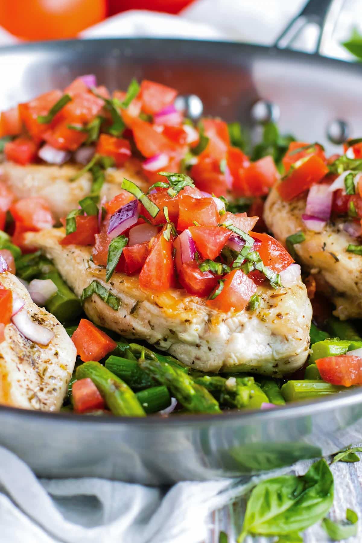 Chicken and asparagus are cooked in a pan then topped with bruschetta.