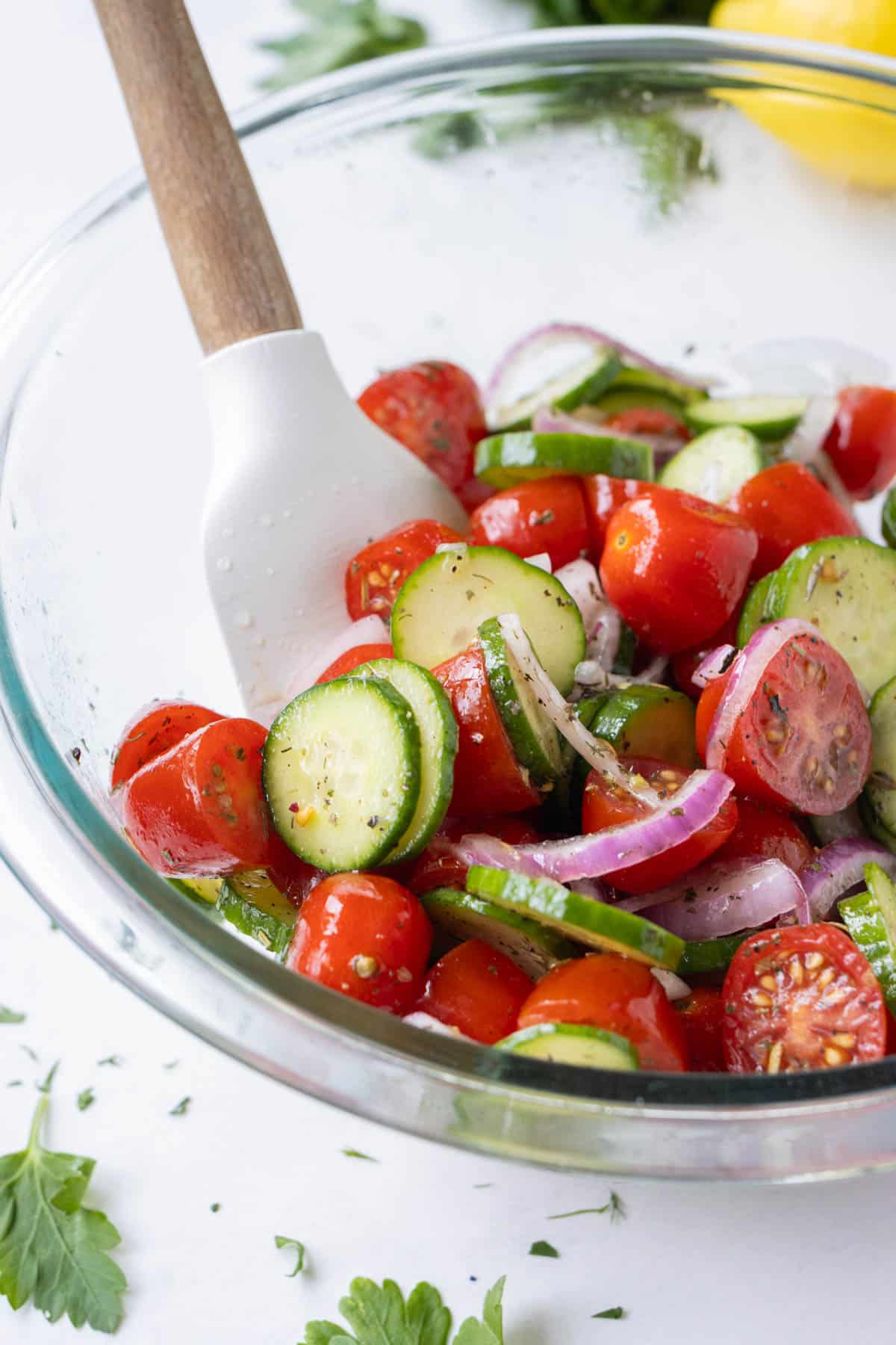 A cucumber tomato salad is stirred together.