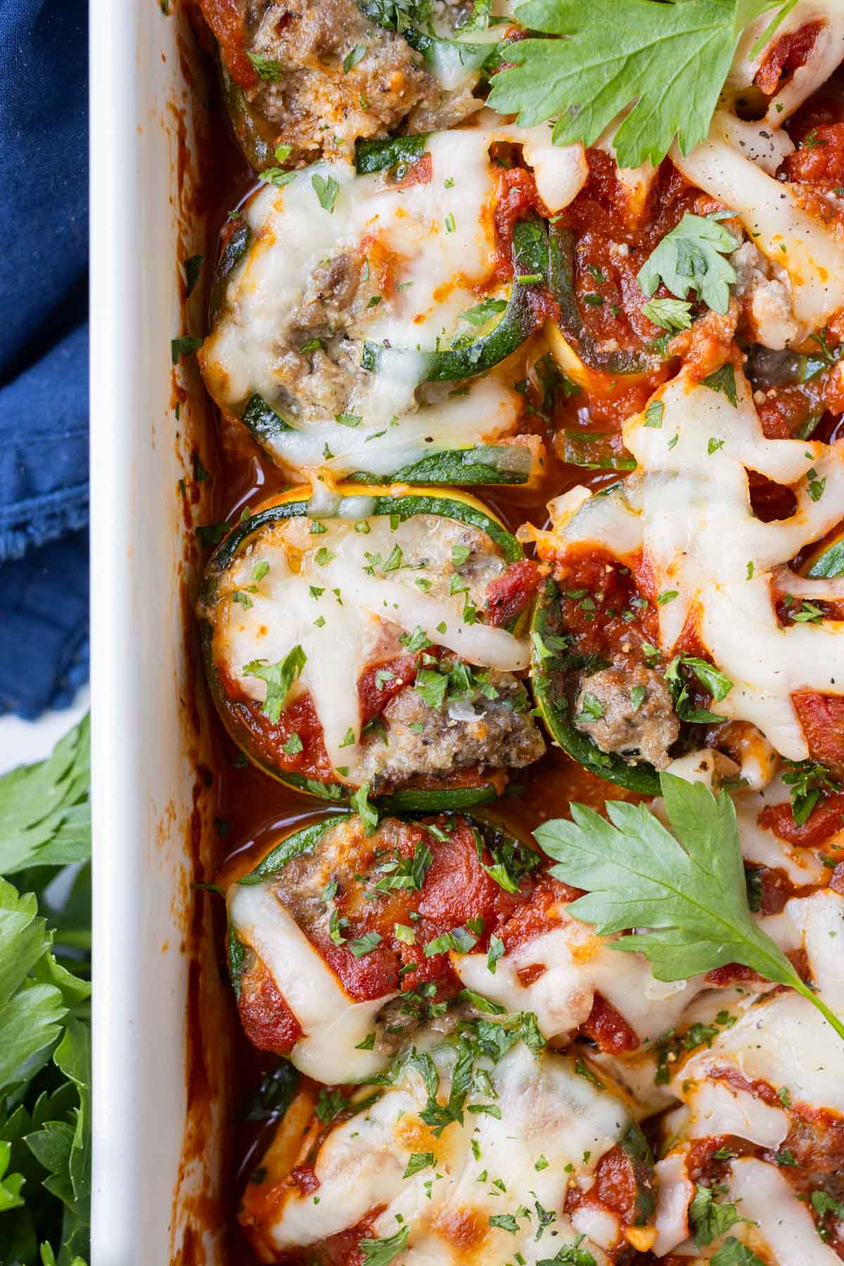 Easy zucchini lasagna roll-ups in red sauce garnished with herbs.