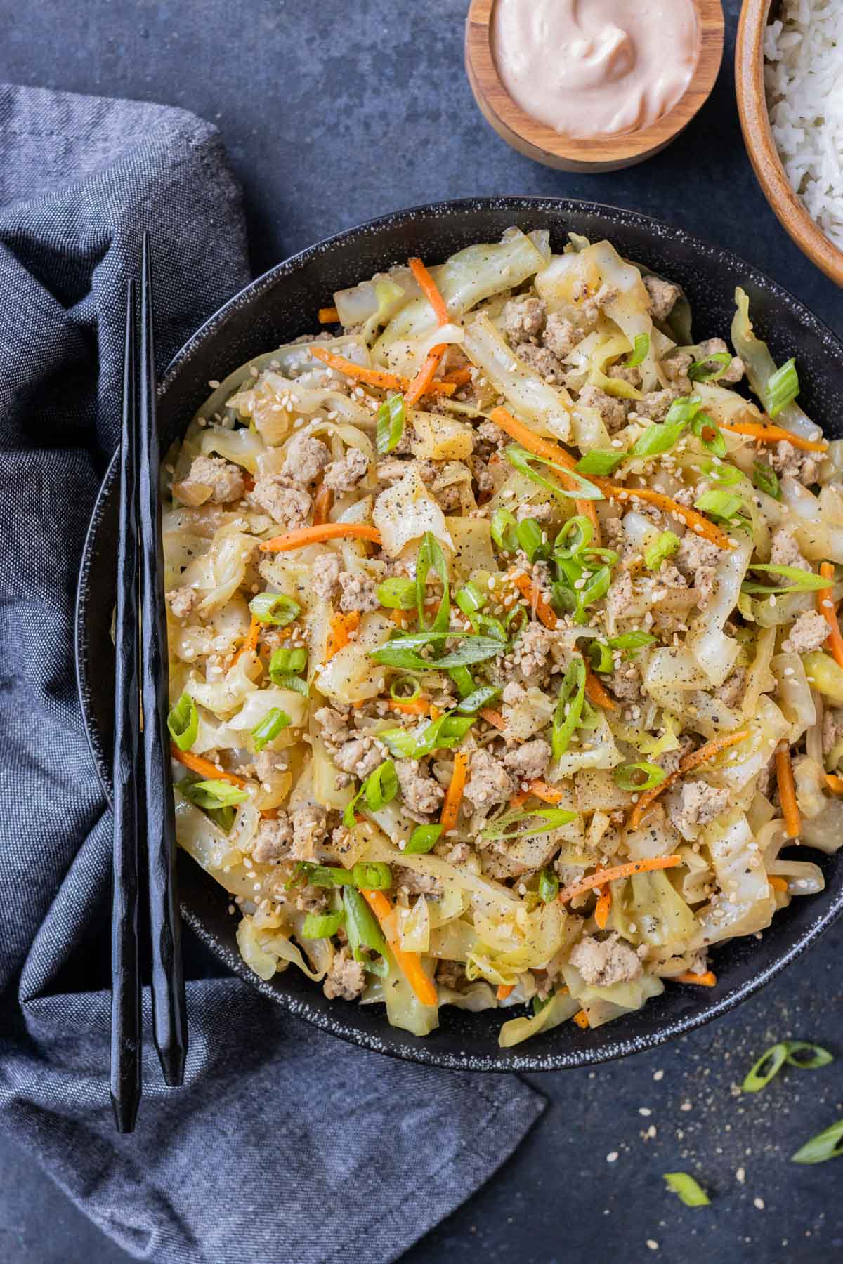 Egg roll in a bowl is served with sriracha mayo and rice.