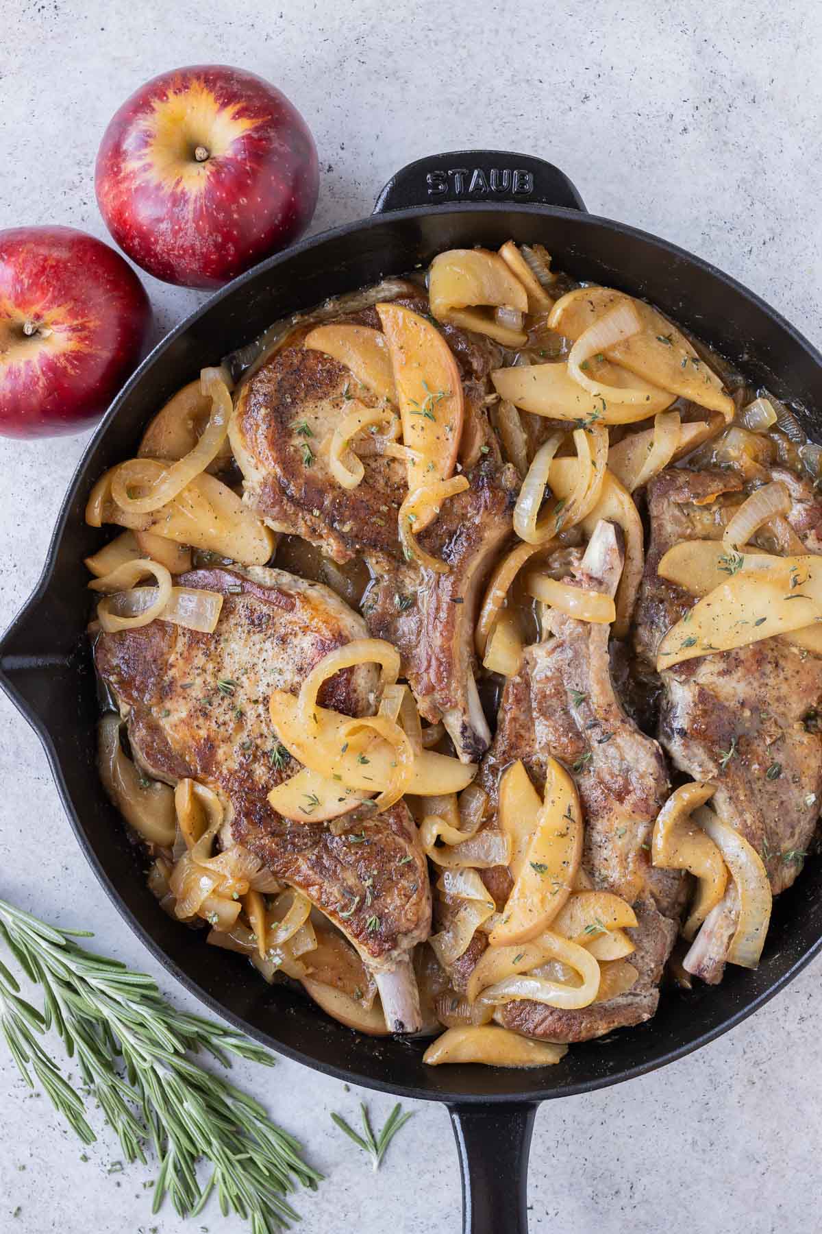 Pork chops are cooked in a skillet with apples and onions.