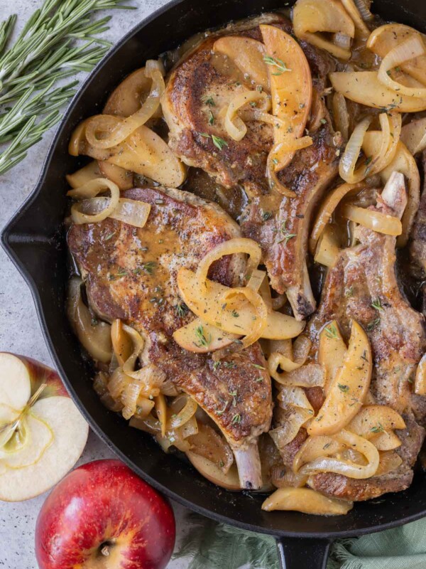 Pork chops are cooked in a skillet with apples and onions.