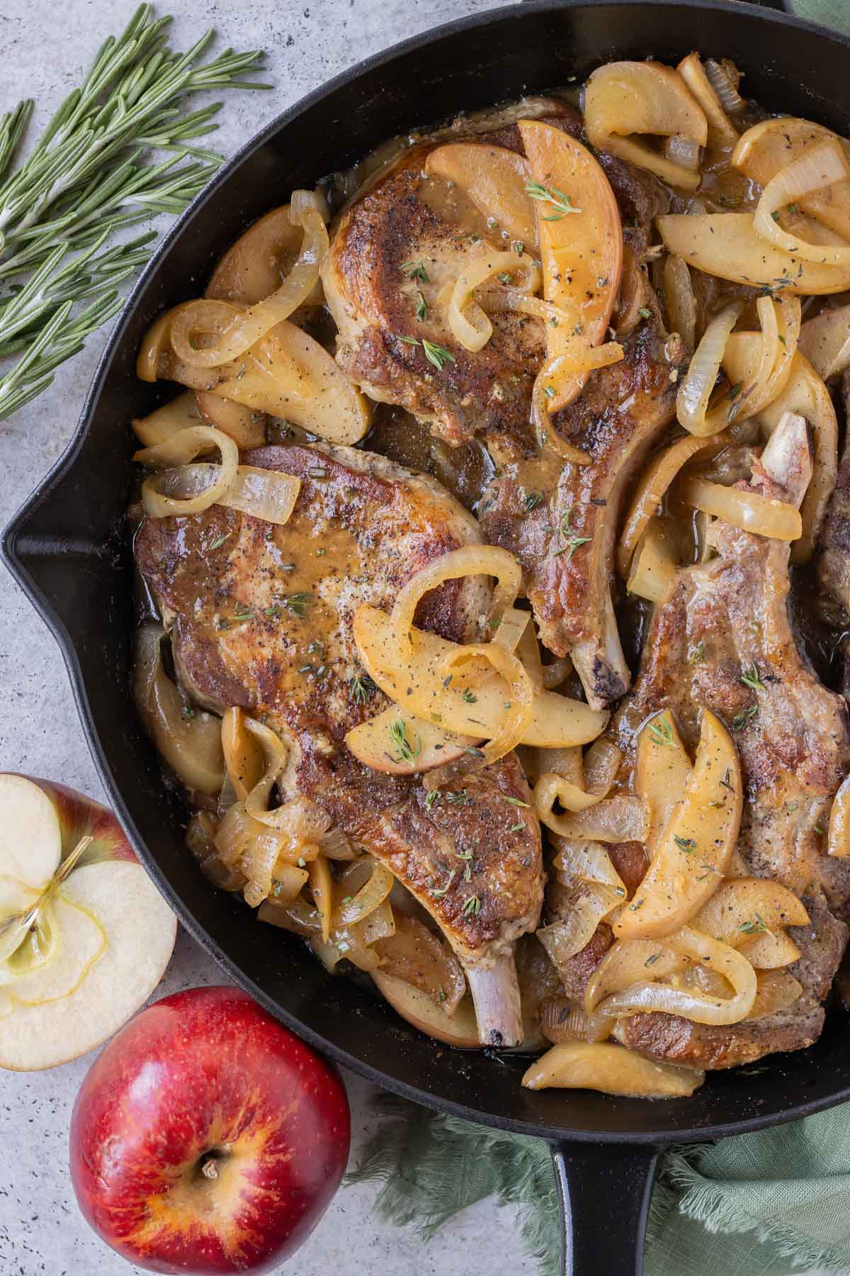 Pork chops are cooked in a skillet with apples and onions.