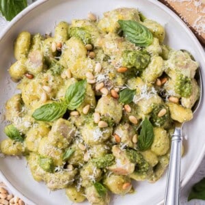 Creamy pesto gnocchi with chicken is in a bowl with a serving spoon.