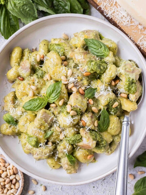 Creamy pesto gnocchi with chicken is in a bowl with a serving spoon.