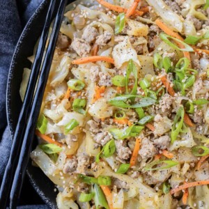 A low-carb egg roll bowl is in a black bowl with green onions.