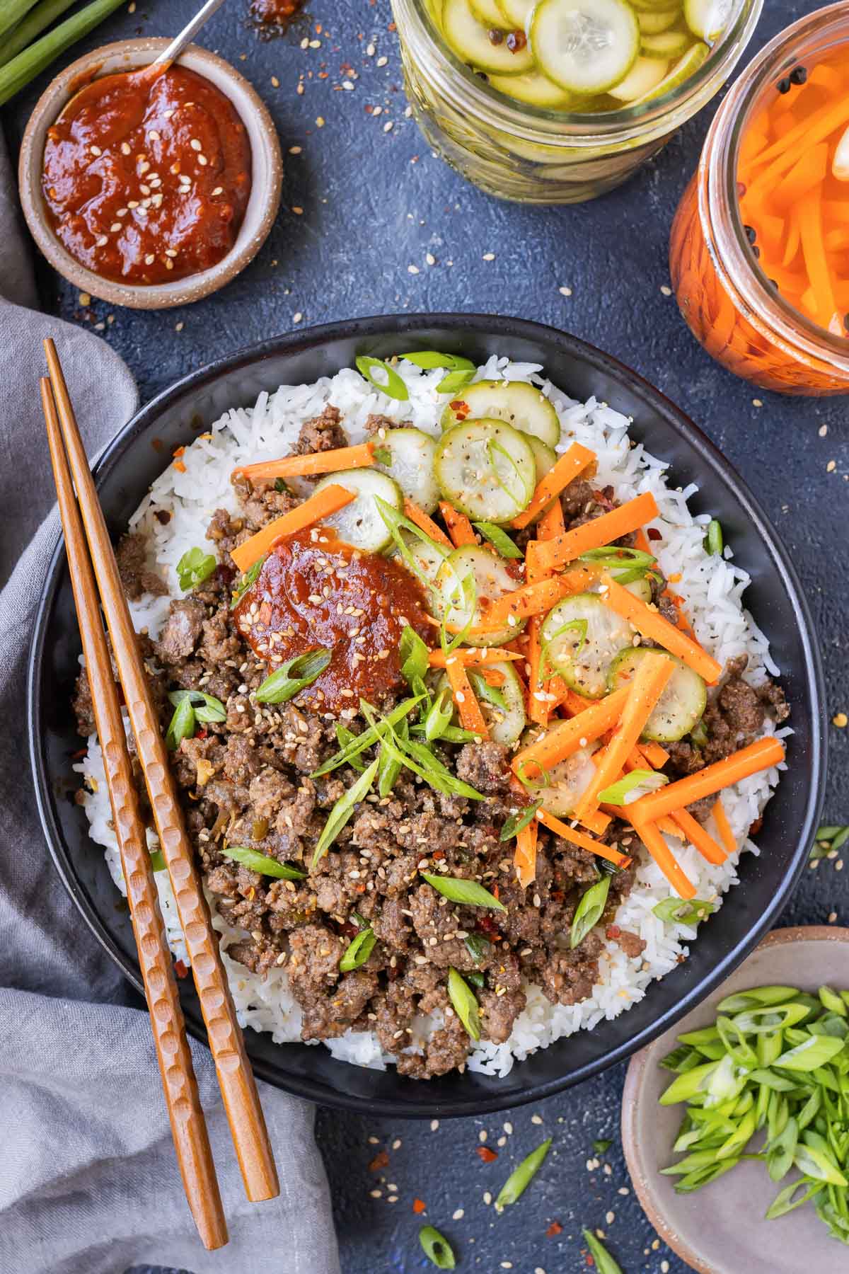 Korean beef is served over rice with pickled carrots and cucumbers with a side of gochujang sauce for an easy dinner.