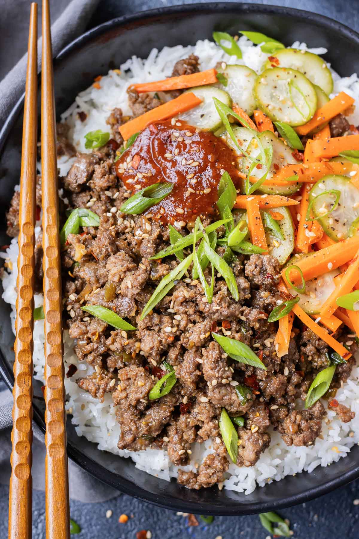 An easy homemade korean beef recipe is served with gochujang and pickled veggies with chopsticks.