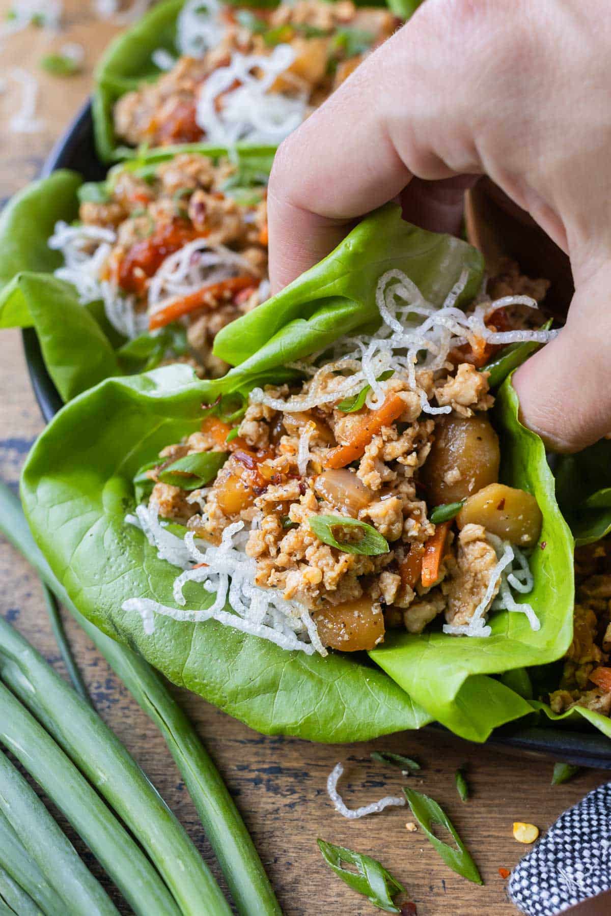 A copycat PF Chang's chicken lettuce wrap is picked up by a hand.